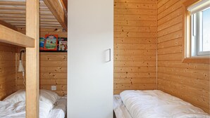 Una camera in legno con due letti, una finestra e uno scaffale con libri.