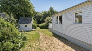 En bostadsfastighet med ett hus och ett litet förråd, omgiven av tät vegetation.