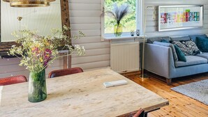 Ein modernes Wohnzimmer mit einem Holzespeisetisch, einer Blumenvase, einem grauen Sofa und einer Heizung.