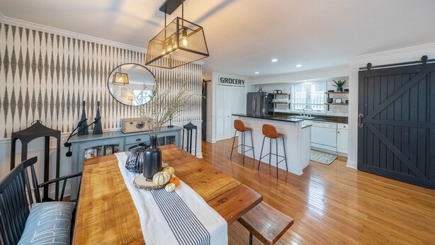 A dining area with a wooden table, chairs, and a hanging light fixture.