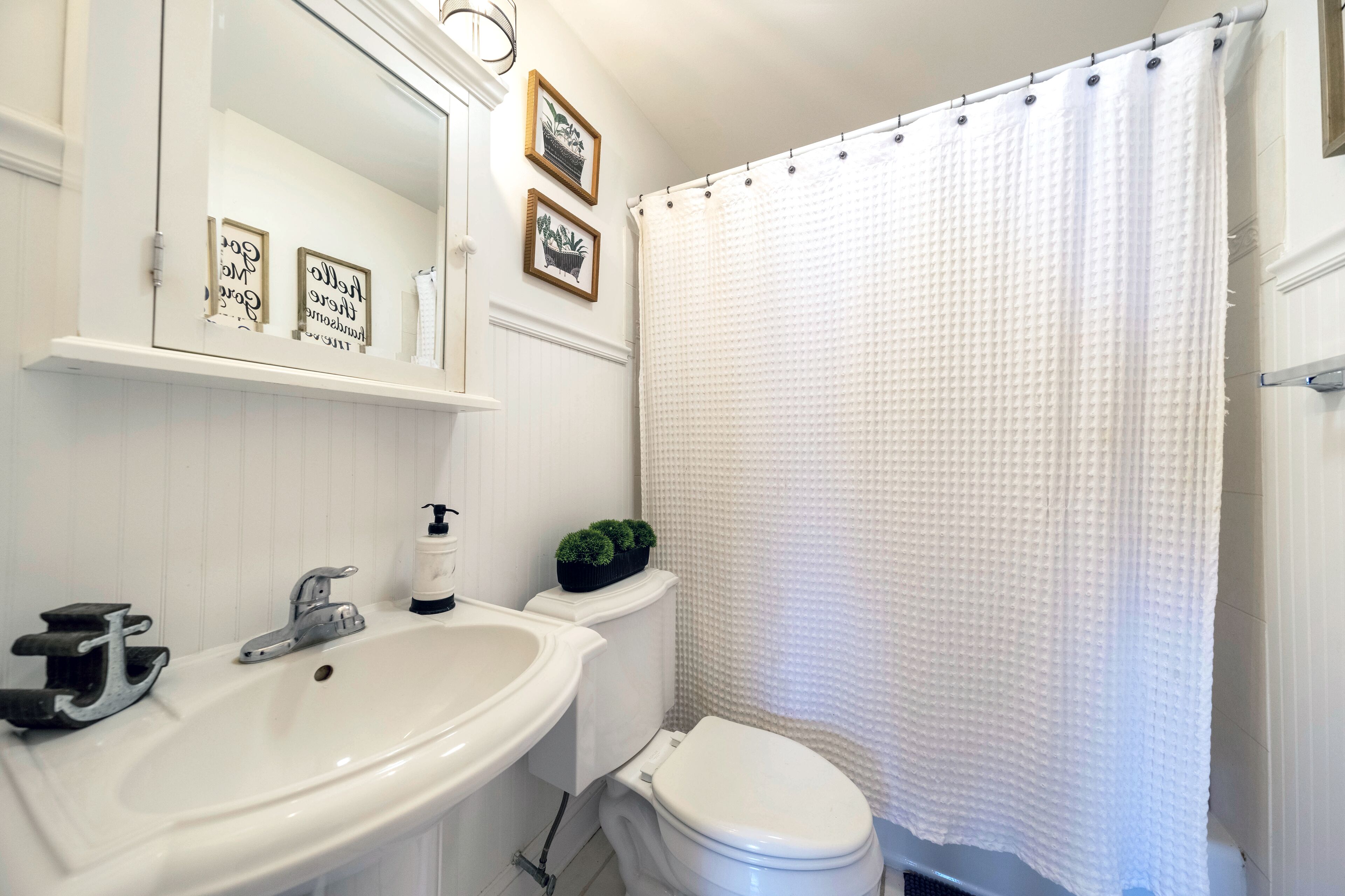 Une salle de bain avec un lavabo blanc, des toilettes et un rideau de douche.