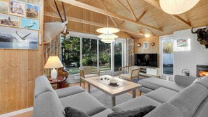 A cozy living room with a fireplace, a TV, and a dining area with a table and chairs. - 3 bedroom gorgeous home in Rønne (Rønne)