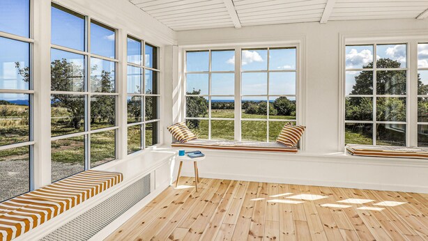 A room with large windows, a wooden floor, and a view of a green landscape. - 5 bedroom nice home in Svaneke (Svaneke)