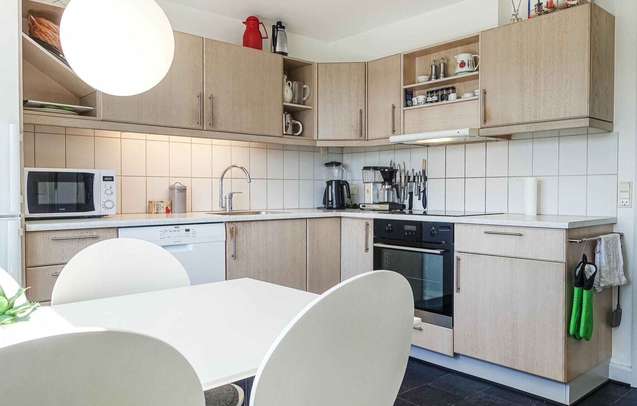 Cuisine moderne équipée d’un four à micro-ondes, d’une machine à café et d’un lave-vaisselle. On y trouve également une table à manger avec des chaises.