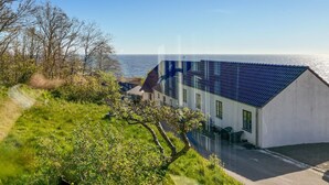 Una casa sul lungomare con tetto blu, pareti bianche e vista mare.