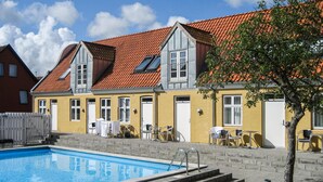 A hotel with a swimming pool, outdoor seating, and a red-tiled roof. - Stunning apartment in Gudhjem with WiFi (Gudhjem)