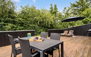 An outdoor deck with a table and chairs, a grill, and a wooden fence. - Awesome home in Tarm with kitchen (Tarm)