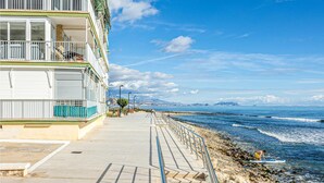 A coastal building with balconies overlooking the sea, a paved walkway, and a rocky shoreline. - Pet friendly apartment in El Campello with WiFi (El Campello)