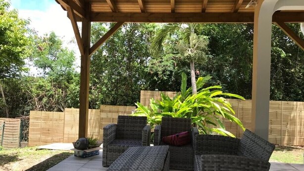 An outdoor patio with wicker furniture and a large plant. - Elegant, recently renovated apartment (Sainte-Anne)
