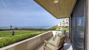 Un balcone con vista sull'oceano, una zona verdeggiante e un edificio sullo sfondo.