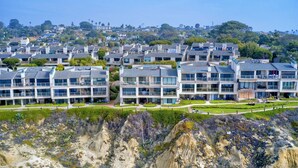Una zona residenziale costiera con edifici moderni a più piani, cielo sereno e un litorale roccioso.