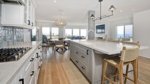 Una cucina moderna con un'isola grande, mobili bianchi e vista sull'esterno.