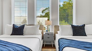 A hotel room with two beds, a nightstand with a lamp, and large windows with blinds. - *SLEEPS 12* Keep the Secret *EAST NASH6* 4BR* 4BA* (Nashville)