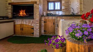 A kitchen with a stone fireplace, wooden cabinets, and a window. - Stunning home in Cehegín (Cehegín)