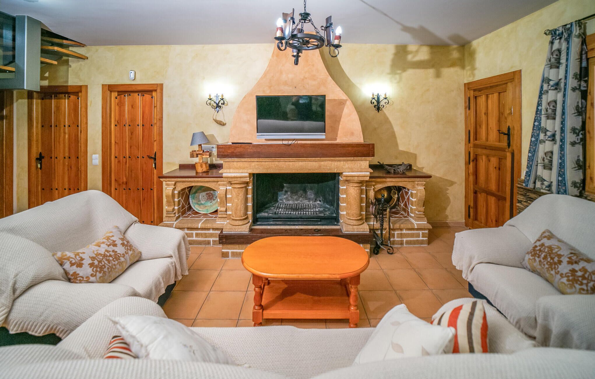 Una sala de estar con chimenea, dos sofás, una mesita de centro y una araña.