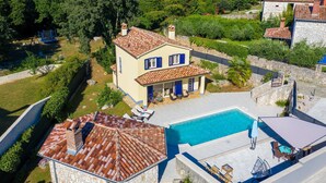 Une maison à deux étages avec une piscine, des murs en pierre et un jardin.