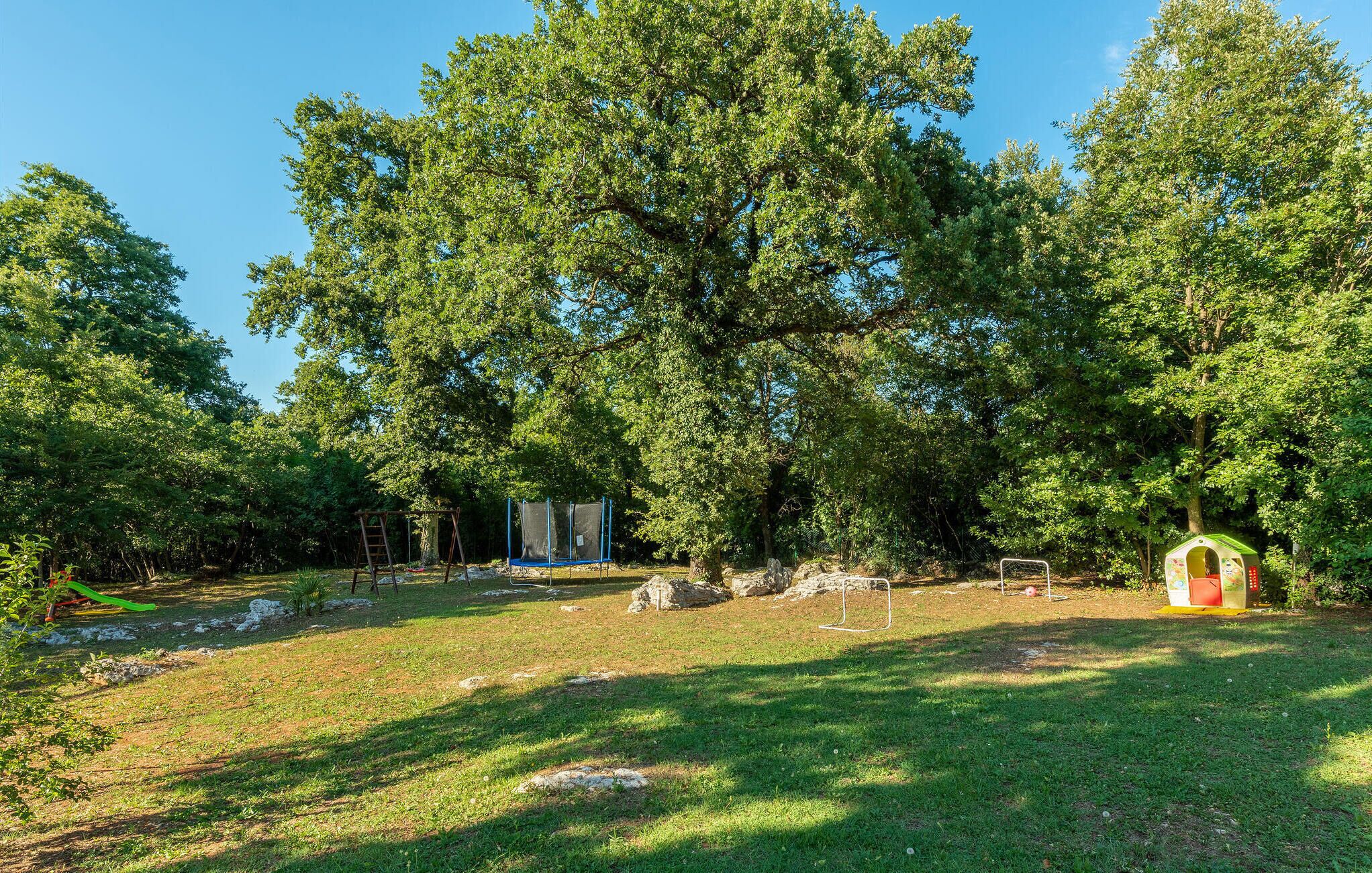 A park with a swing set, a trampoline, and a small playhouse.