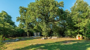 Un parc équipé d’une balançoire, d’un trampoline et d’une petite maison de jeu.