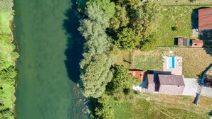 An aerial view of a riverside property with a swimming pool, a red-roofed building, and lush greenery. - Awesome home in Mirkopolje (Mirkopolje)