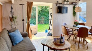 Un salon chaleureux avec un canapé, une table basse ronde et un coin repas comprenant des chaises et une table.
