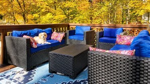An outdoor seating area with wicker furniture and blue cushions, surrounded by autumn foliage. - Visit Willow’s Place! All season Pocono Retreat!  Kayaks, Canoes and Pedal Boat! (Lake Ariel)