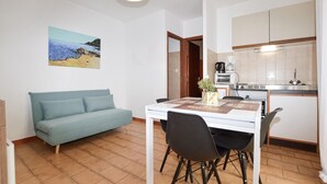 A compact living space with a sofa, dining table, chairs, a kitchen area with appliances, and a painting on the wall. - 1 bedroom amazing apartment in Monticello (Monticello)
