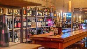 A bar with shelves of wine bottles, a wooden counter, and a candelabra with candles. - hochwertige Ferienwohnung (Matrei in Osttirol)