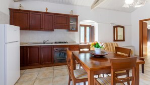 Una cocina con armarios de madera, una estufa y una mesa de comedor con sillas.