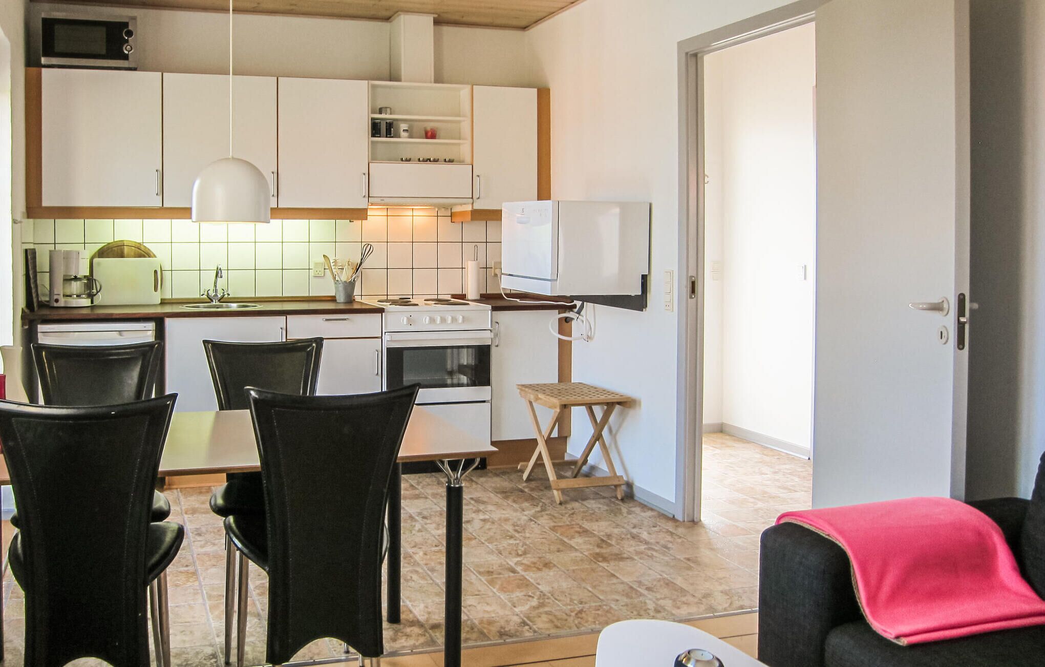 A compact kitchen with white cabinets, a microwave, a coffee maker, and a small dining area with chairs and a table.