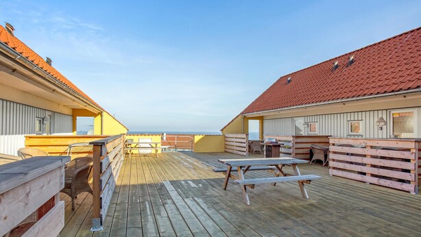 A wooden deck with picnic tables and chairs, overlooking the sea. - Cozy apartment in Gudhjem with WiFi (Gudhjem)
