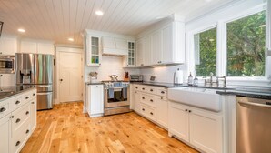 Una cocina moderna con armarios blancos, electrodomésticos de acero inoxidable y piso de madera.