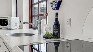 Een moderne keuken met een roestvrijstalen spoelbak, een witte toaster, een fles wijn en een bordenrek met ruitjes.