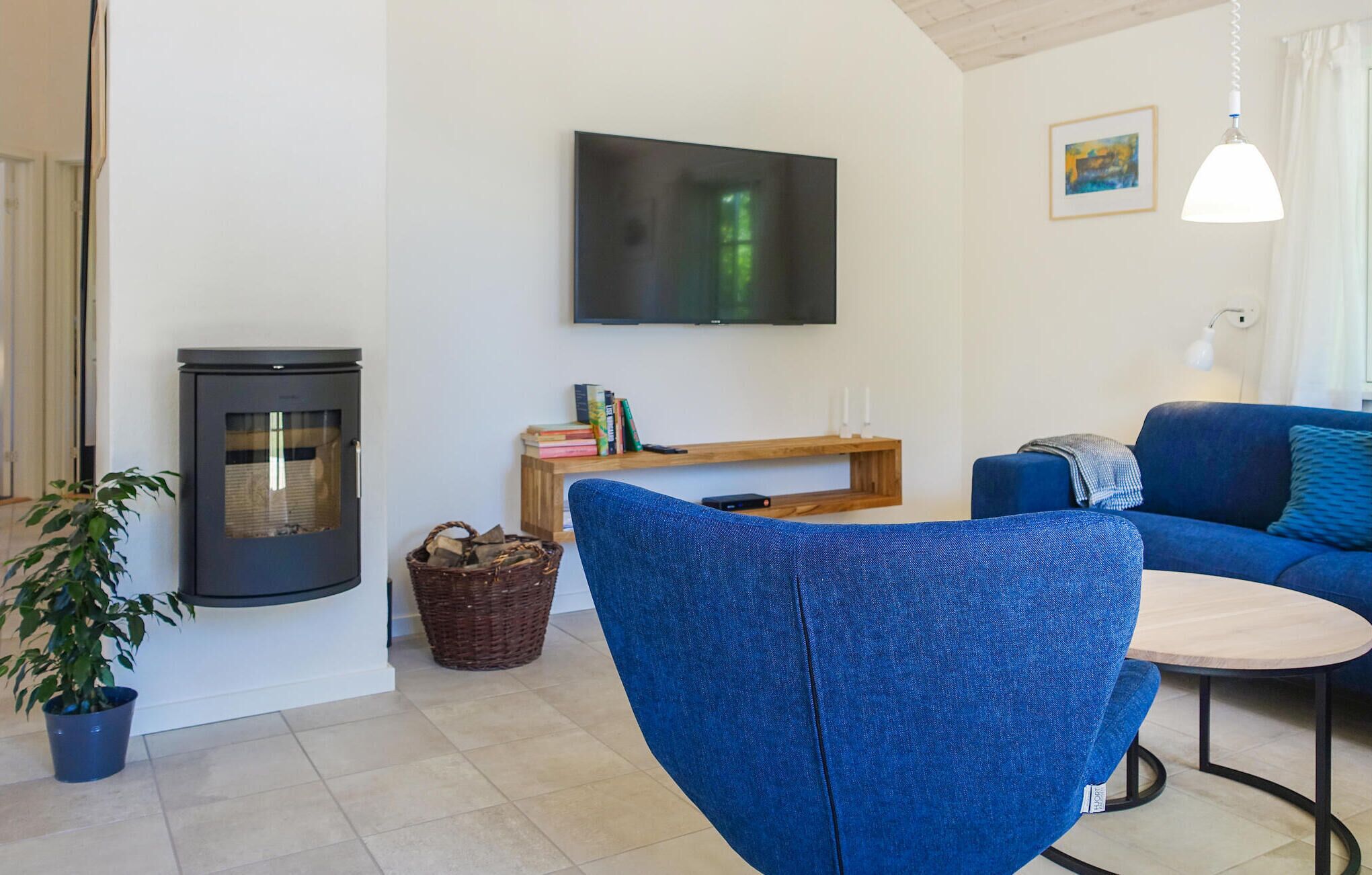 A living room with a blue chair, a fireplace, a TV, a bookshelf, and a blue sofa.