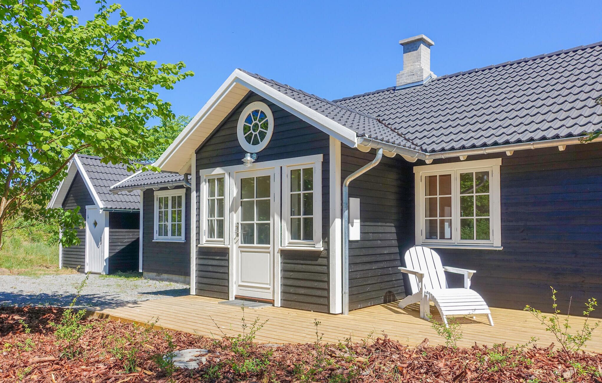 A wooden cabin with a gabled roof, a front porch, and a deck area with a chair.