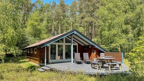 A wooden cabin with a porch, outdoor seating, and a deck.