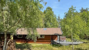 A wooden cabin with a tiled roof, surrounded by trees.