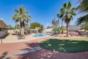 A backyard with a swimming pool, palm trees, a covered patio, and a lawn. - Spacious 4BR Near Strip with Private Pool, Free Parking (Las Vegas)