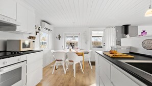 A modern kitchen with white cabinetry, a central island, and a dining area with white chairs. - Amazing home in Haderslev with WiFi (Haderslev)