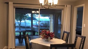 Ein Essbereich mit einem runden Tisch, sechs Stühlen, einer Deckenleuchte und Blick durch eine Glastür auf eine Außenpatio.