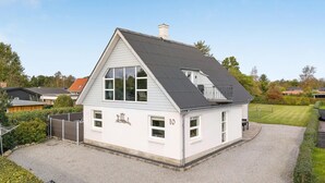 A white two-story house with a grey roof, number 10, surrounded by a gravel driveway and a well-maintained lawn. - 5 bedroom nice home in Hadsund (Hadsund)