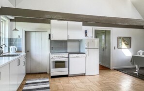 Kitchen features a central island with sink, stove, and dishwasher, surrounded by light-colored cabinetry and a tiled backsplash.