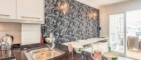 A modern kitchen with a black and white patterned backsplash, stainless steel appliances, and a large window providing natural light.