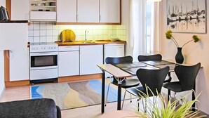 Una cocina moderna con armarios blancos, una olla amarilla y una mesa de comedor con cuatro sillas.