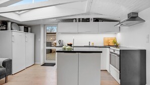 A modern kitchen with white cabinetry, a central island, and a skylight above. - Awesome home in Sjølund with WiFi (Sjølund)