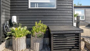 A building with a dark exterior, a window with two candles, and two wicker baskets with plants. - Awesome home in Sjølund with WiFi (Sjølund)