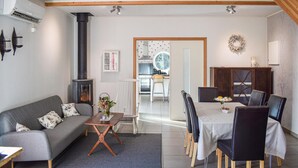A cozy living room with a sofa, a coffee table, and a dining area with a table and chairs. - Cozy apartment in Långaryd with WiFi (Långaryd)