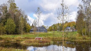 A rural landscape with a large barn and a smaller house, surrounded by trees and a pond. - Cozy apartment in Långaryd with WiFi (Långaryd)