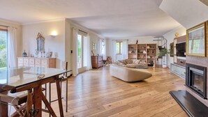 A spacious living room with a wooden floor, a large sofa, a fireplace, and a bookshelf. - Gorgeous home in Prelà (Prelà)