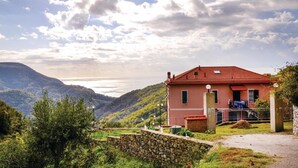 Ein Haus mit rotem Dach, einer Steinmauer und Blick auf das Meer.