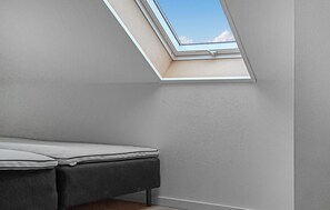 A room with a skylight, a bed, and a wall-mounted heater. - Nice apartment in Allinge (Allinge)